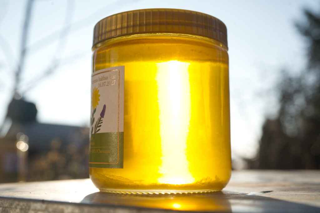 Glas mit flüssigem Sommerhonig, von der Sonne durchleuchtet